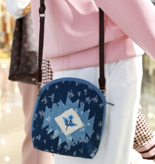 A fabric shell crossbody bag with handmade embroidery and a zipper