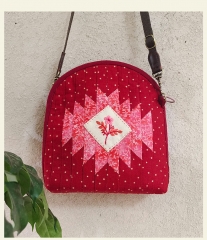 A fabric shell crossbody bag with handmade embroidery and a zipper