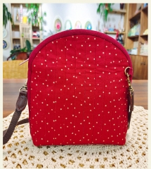 A fabric shell crossbody bag with handmade embroidery and a zipper