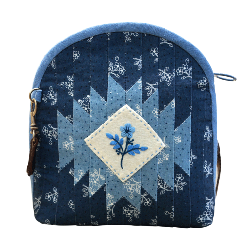 A fabric shell crossbody bag with handmade embroidery and a zipper